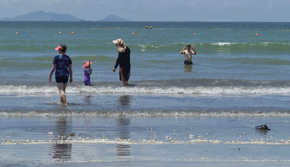 Buih putih menggumpal saat pengunjung bermain air di sebuah pantai di Hong Kong, Senin (7/8). Kecelakaan kapal pengangkut minyak sawit di perairan sekitar Hong Kong memaksa negara di bawah kedaulatan China itu menutup 10 pantainya. (Anthony WALLACE / AFP)