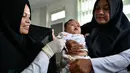 Petugas menyuntikan Vaksin Campak dan Rubella (MR) kepada bayi saat dilakukan imunisasi di sebuah puskesmas, Banda Aceh, Rabu (19/9). Pelaksanaan vaksinasi MR di Aceh sempat ditunda karena adanya enzim babi di dalam vaksin. (CHAIDEER MAHYUDDIN / AFP)