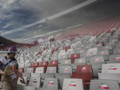 Seorang tenaga relawan melintasi deretan kursi di Stadion Utama Gelora Bung Karno, Jakarta, Jumat (9/8/2018). Lokasi ini akan dijadikan venue dari invitation tournament cabang atletik. (Bola.com/Vitalis Yogi Trisna)