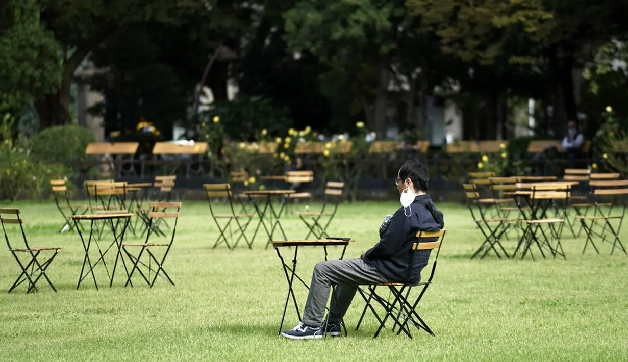Seorang pria yang mengenakan masker pelindung untuk membantu mengekang penyebaran virus corona COVID-19 beristirahat di kafe terbuka, Tokyo, Jepang, Senin (12/10/2020). Tokyo mengonfirmasi lebih dari 70 kasus COVID-19 pada hari Senin. (AP Photo/Eugene Hoshiko)