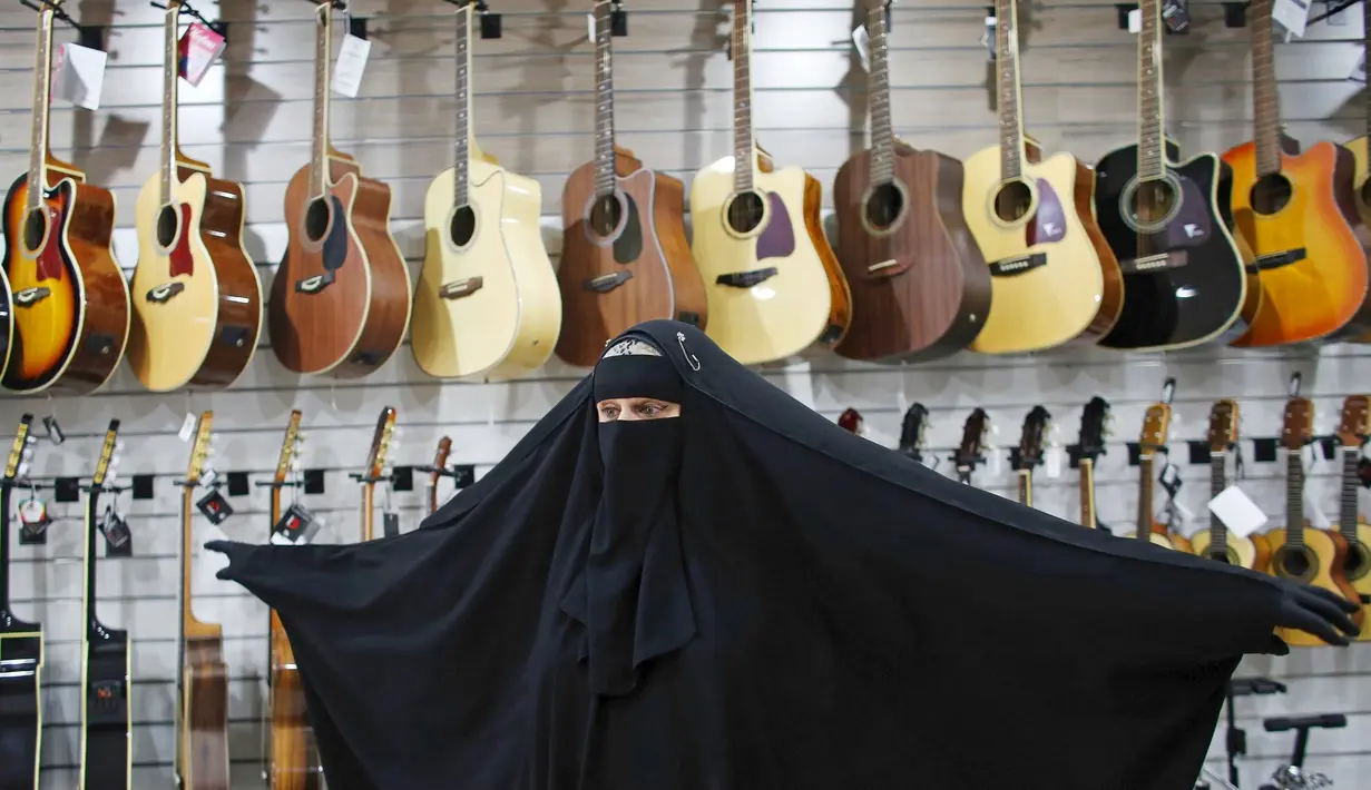 Gisele Marie mengerakan tubuhnya di depan gitar sebuah toko yang menjual alat musik di Sao Paulo, Brasil (13/8/2015). Marie merupakan cucu dari kakek beragama Katolik Jerman, ia masuk Islam setelah ayahnya meninggal pada tahun 2009. (REUTERS/Nacho Doce)