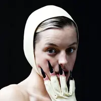 Emma Corrin dalam balutan gaun dari Miu Miu bernuansa lemon dengan bonet (topi) senada, dan kuku palsu hitam yang terkesan dramatis. Foto: Instagram @emmalouisecorrin.