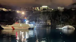 Selebaran foto pada 20 Januari 2021 menunjukkan bangkai paus berukuran besar di pelabuhan Sorrento saat ditarik oleh penjaga pantai Italia menuju pelabuhan Napoli. Bangkai paus itu akan diautopsi oleh ahli biologi kelautan dan ahli lain yang mencari penyebab kematiannya. (HO/GUARDIA COSTIERA/AFP)