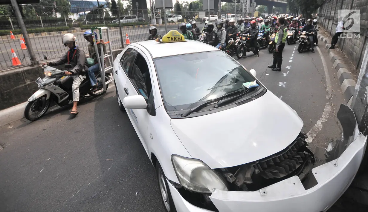 Pengendara sepeda motor tersendat saat melintasi lokasi kecelakaan taksi menabrak tiang di Jalan Ahmad Yani, Jakarta, Rabu (1/8). Tidak ada korban jiwa dalam kecelakaan tersebut. (Merdeka.com/Iqbal Nugroho)