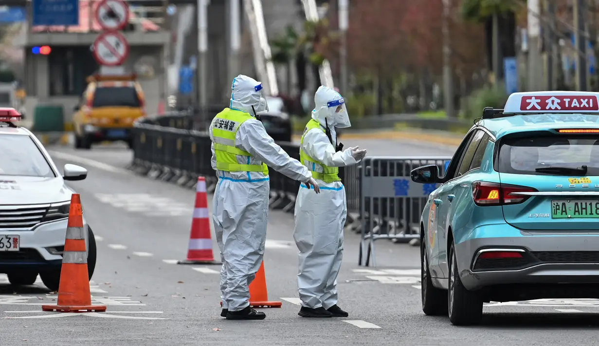 Petugas polisi yang mengenakan pakaian pelindung mengontrol akses ke terowongan ke arah distrik Pudong yang dikunci sebagai tindakan melawan virus corona Covid-19, di Shanghai (28/3/2022). (AFP/Hector Retamal)