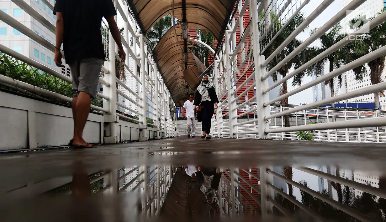 Warga melintasi Jembatan Penyeberangan Orang (JPO) yang rusak di kawasan Dukuh Atas, Jakarta, Rabu (12/12). Rusaknya JPO membahayakan pejalan kaki yang melinatas karena jembatan menjadi licin saat hujan. (Liputan6.com/JohanTallo)