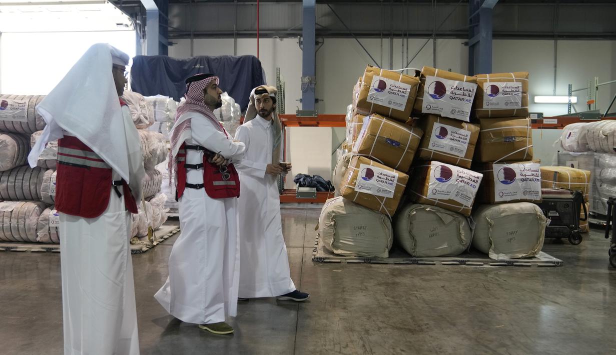 Karyawan Bulan Sabit Merah Qatar melewati pasokan paket bantuan yang akan dikirim untuk wilayah yang dilanda gempa di Turki, di Pangkalan Udara Al-Udeid di Qatar, Selasa, 7 Februari 2023. Gempa bumi dahsyat melanda Turki tenggara dan Suriah Senin dini hari, merobohkan ratusan bangunan serta menewaskan dan melukai ribuan orang. (AP Photo/Kamran Jebreili)