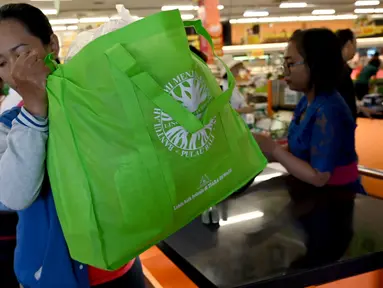Seorang konsumen menggunakan tas belanja nonplastik untuk mengemas barang belanjaan di sebuah supermarket di Denpasar, 16 Juli 2019. Bali menerapkan pelarangan penggunaan plastik sekali pakai yang tertuang dalam Peraturan Gubernur (Pergub) Nomor 97 Tahun 2018. (SONNY TUMBELAKA/AFP)