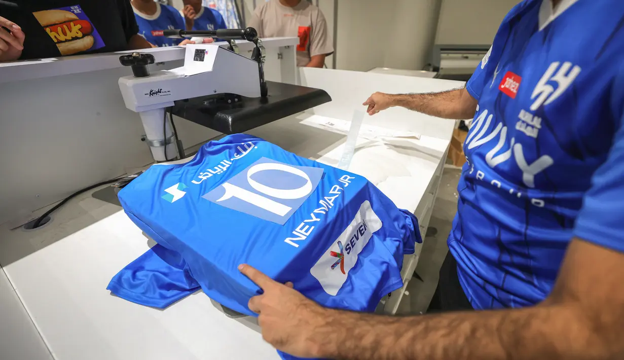 Pekerja toko tampak sibuk menyablon nama Neymar dan nomor punggung 10 pada jersey Al Hilal. (Photo by Fayez Nureldine / AFP)