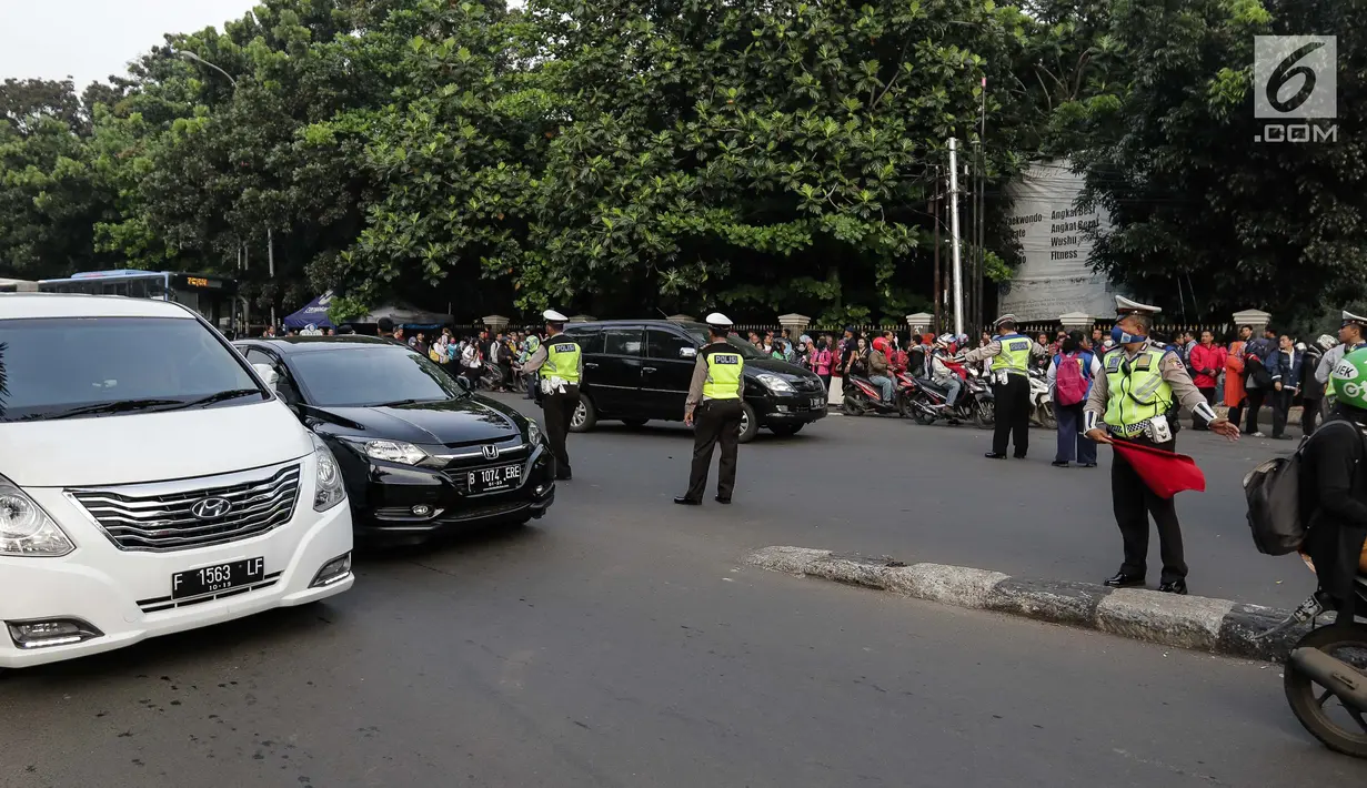 Petugas polisi mengatur lalu lintas saat pemberlakuan sistem ganjil genap di pintu masuk Gardu Tol Cibubur 2, Jakarta, Senin (16/4). Kebijakan ini diterapkan untuk mengurai kemacetan di ruas Tol Jagorawi. (Liputan6.com/Faizal Fanani)