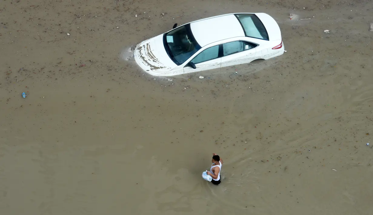 Seorang pria melintasi sebuah jalan yang terendam banjir menyusul hujan lebat di Kegubernuran Mubarak Al-Kabeer, Kuwait (29/11/2020). Hujan lebat melanda Kuwait pada Sabtu (28/11) malam dan Minggu (29/11) pagi waktu setempat. (Xinhua/Asad)
