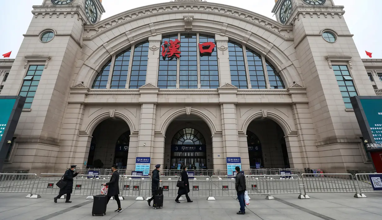 Orang-orang berjalan melewati Stasiun Kereta Api Hankou yang ditutup di Wuhan, Provinsi Hubei, China, Kamis (23/1/2020). Pemerintah China mengisolasi Kota Wuhan yang berpenduduk sekitar 11 juta jiwa untuk menahan penyebaran virus corona. (Chinatopix via AP)