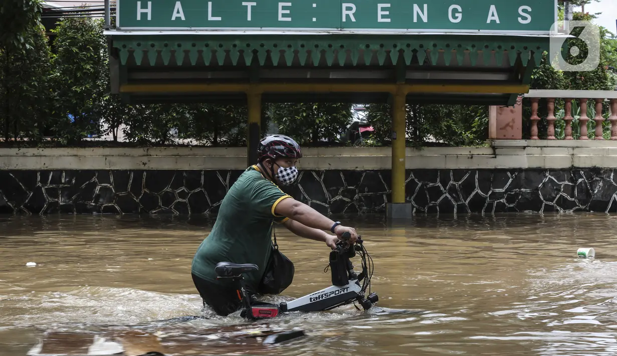 Warga menuntun sepedanya saat melewati banjir di kawasan Tendean Jakarta, Sabtu (20/2/2021). Curah hujan yang tinggi menyebabkan banjir setinggi orang dewasa di kawasan Tendean. (Liputan6.com/Johan Tallo)