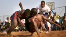 Seorang pegulat menjatuhkan lawannya dalam festival gulat tradisional di Bamako, Mali, 7 April 2019. festival gulati ini digelar setiap tahun di Bamako. (MICHELE CATTANI/AFP)