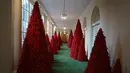 Deretan pohon cemara berwarna merah darah di sepanjang lorong East Colonnade yang didekorasi untuk perayaan Natal di Gedung Putih, Washington DC, Senin (26/11). Tema dekorasi yang diangkat tahun 2018 ini adalah 'American Treasures'. (AP/Carolyn Kaster)