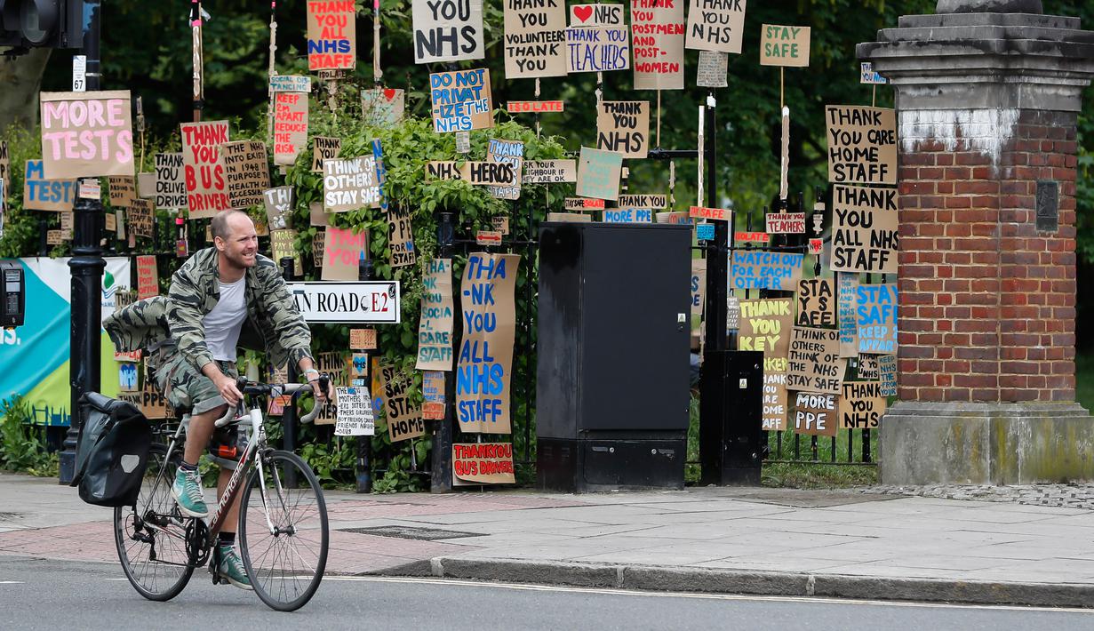 Seorang pria berjalan melewati kumpulan plakat yang dirancang oleh seniman lokal Peter Liversidge untuk mendukung Layanan Kesehatan Nasional (National Health Service/NHS) di London, Inggris, (29/4/2020). (Xinhua/Han Yan)