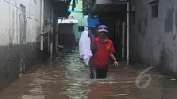 Warga melintasi banjir yang merendam Kampung Pulo, Jatinegara, Jakarta Timur, Selasa (10/2/2015). Sebagian wilayah Jakarta terendam banjir akibat hujan yang terus turun sejak Minggu (8/2) malam lalu. (Liputan6.com/Herman Zakharia)