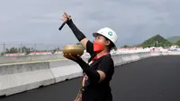 Seorang pawang hujan melakukan ritual saat sesi latihan bebas MotoGP Indonesia di Sirkuit Mandalika, Mandalika, Lombok Tengah, Nusa Tenggara Barat, Jumat (18/3/2022). (AFP/Bay Ismoyo)