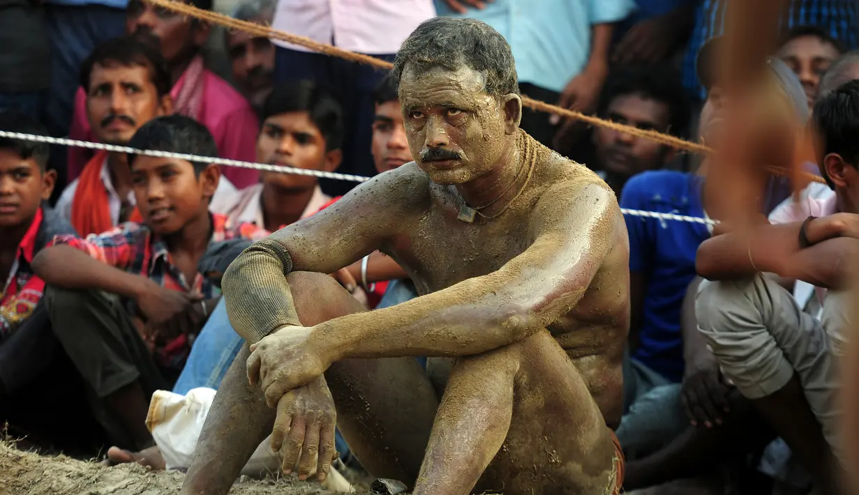 Seorang pegulat dengan tubuh dilumuri tanah duduk usai memenangkan pertandingan gulat tradisional India yang diadakan di desa Rampur, India (7/10). (AFP Photo/Sanjay Kanojia)