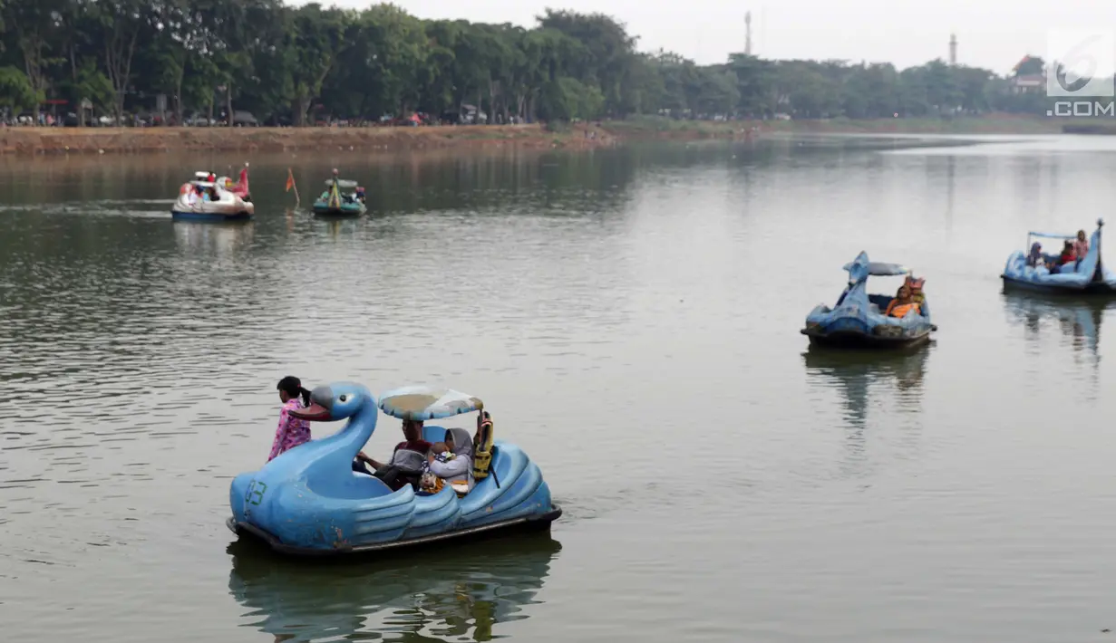 Pengunjung naik perahu bebek kawasan Setu Babakan, Jakarta, Minggu (23/6/2019). Ribuan warga memadati kawasan Setu Babakan untuk berwisata dan menyaksikan beragam acara dalam rangka perayaan HUT ke-492 Jakarta. (Liputan6.com/Helmi Fithriansyah)