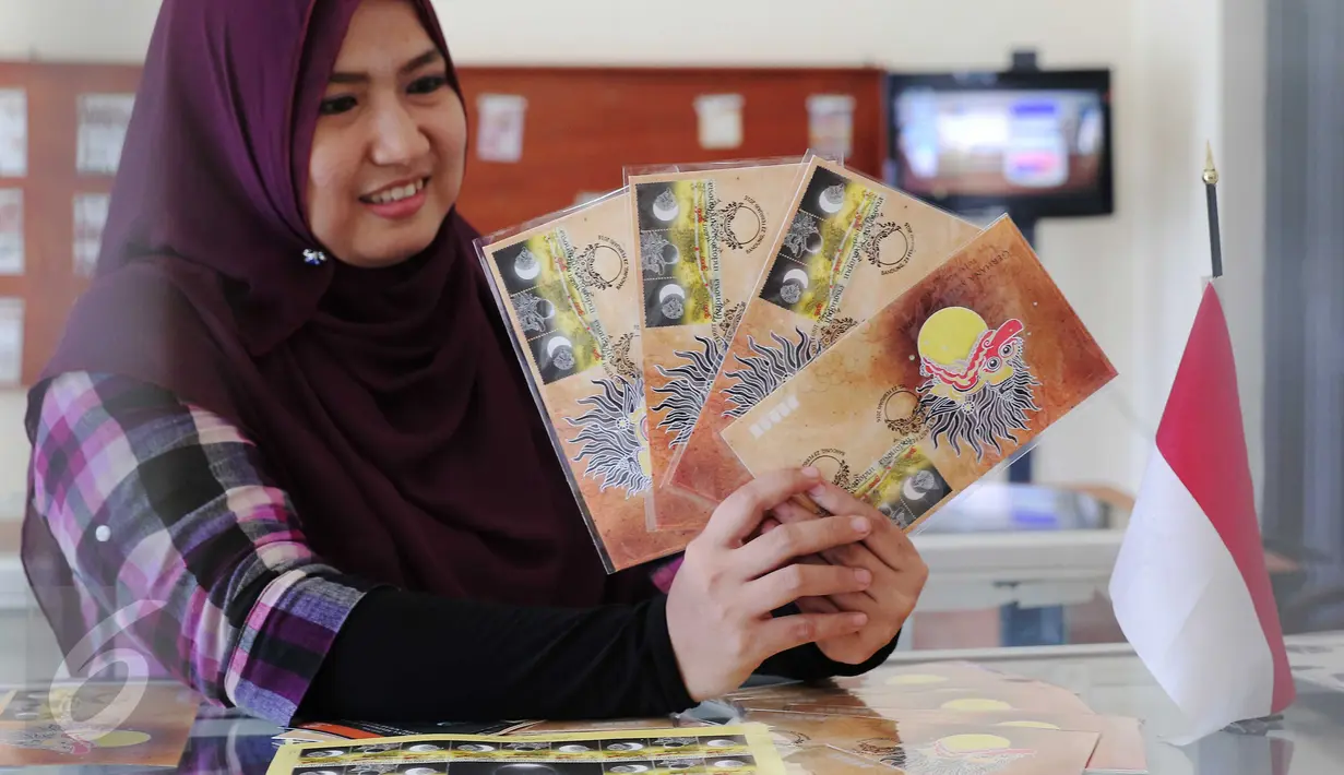Petugas menunjukan perangko edisi Gerhana Matahari Total di Kantor Pos Indonesia, Jakarta, (25/2).Peristiwa  fenomena langka tersebut akan terjadi pada  9 Maret mendatang. (Liputan6.com/Angga Yuniar)