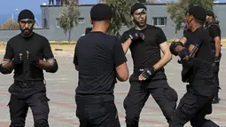 Anggota pasukan keamanan Hamas Palestina melukis wajah mereka saat menunjukkan keterampilan militer mereka saat upacara wisuda di Kota Gaza, Senin (21/2/2022). (AP Photo/Adel Hana)