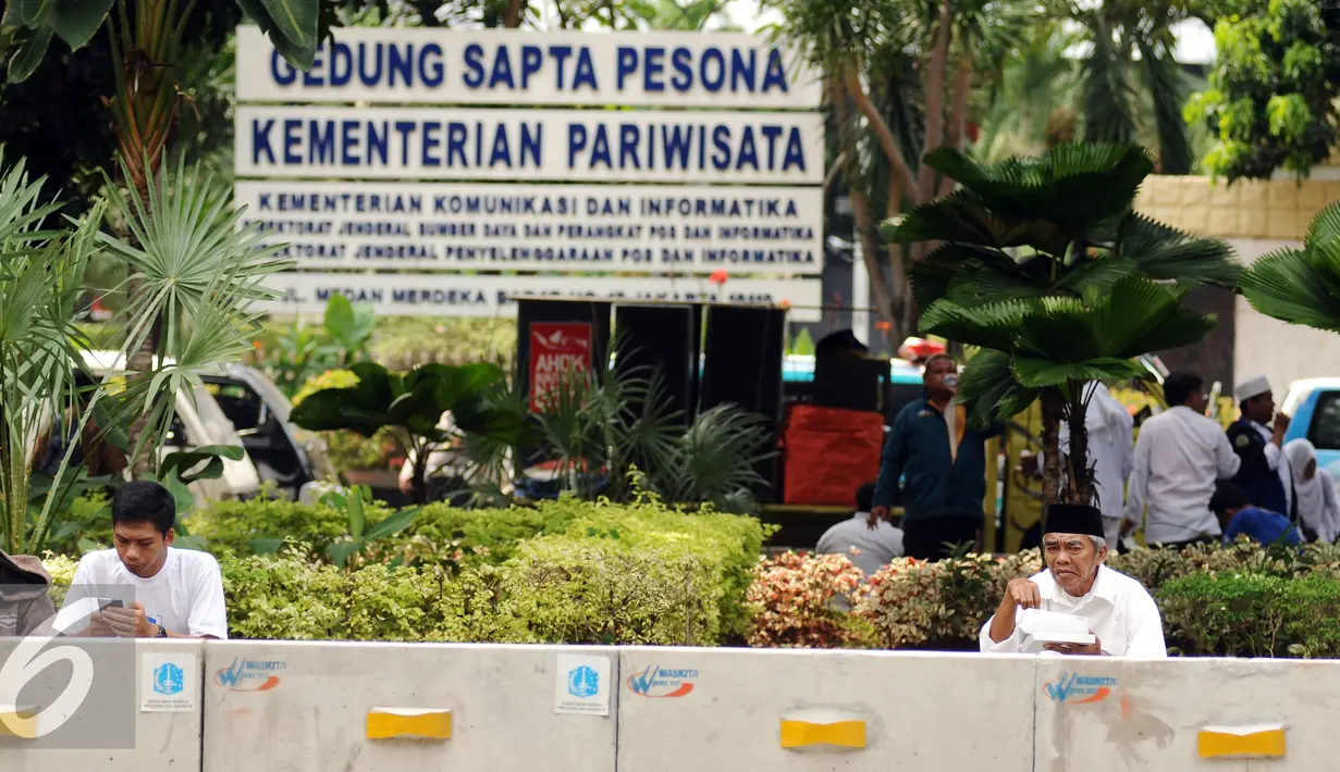 Massa aksi damai beristirahat dan makan siang di pinggir Jalan Merdeka Barat, Jakarta, Jumat (4/11). Massa melakukan aksi di depan Istana Negara menuntut penegakan hukum kasus dugaan penistaan agama. (Liputan6.com/Helmi Fithriansyah)