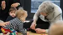 Perdana Menteri Inggris Theresa May berinteraksi dengan bayi saat berkunjung ke pusat kesehatan di London, Inggris, Kamis (22/11). Sejumlah bidang kementerian pernah Theresa geluti sebelum menjadi PM Inggris.(Andrew Matthews/Pool via AP)