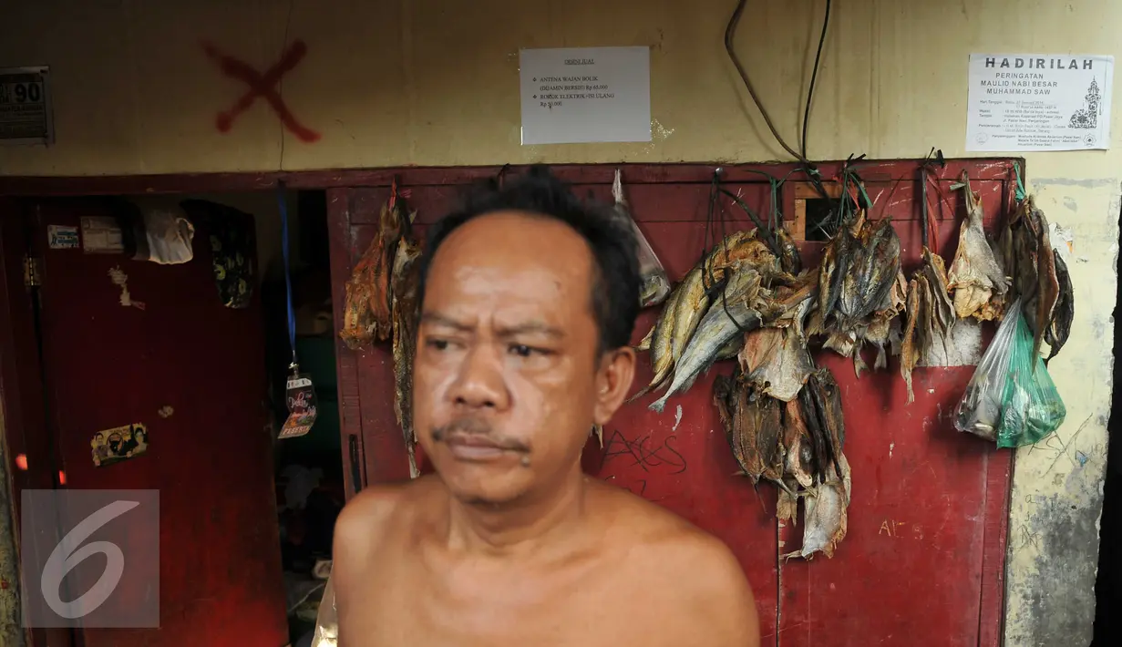 Warga berada di depan rumahnya di Kampung Aquarium, Jakarta Utara, Senin (28/3). Tanda X yang berada di atas pintu sebagai tanda rumah tersebut masuk dalam rencana penggusuran. (Liputan6.com/Gempur M Surya)