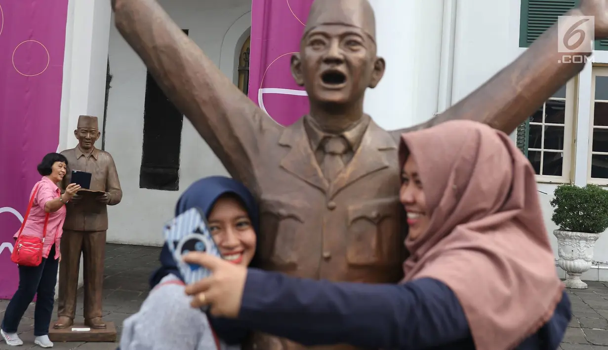 Pengunjung berfoto patung Presiden pertama RI Sukarno dipajang di depan Museum Fatahillah, kawasan Kota Tua, Jakarta, Rabu (15/11). Sebanyak 10 patung Sukarno disajikan dalam rangka Jakarta Biennale 2017. (Liputan6.com/Immanuel Antonius)