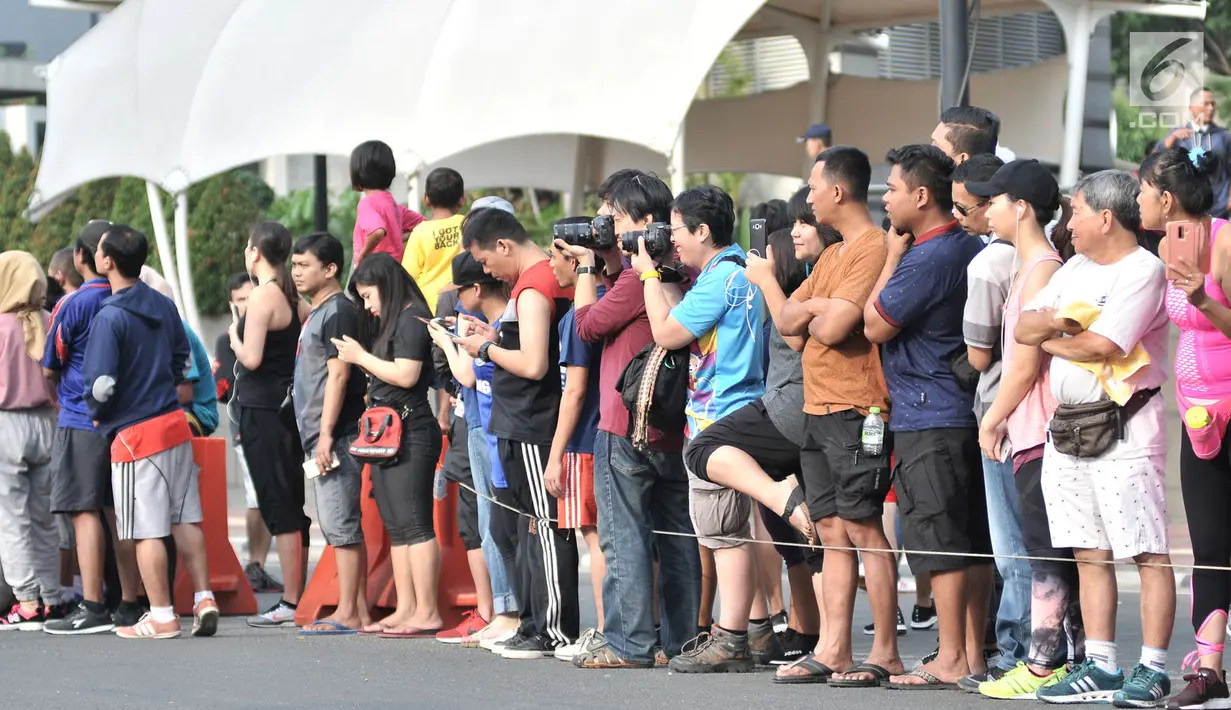 Warga berfoto-foto saat menunggu peserta lomba lari maraton Asian Games 2018 di kawasan MH Thamrin, Jakarta, Minggu (26/8). (Merdeka.com/Iqbal S. Nugroho)
