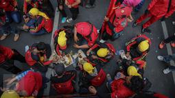 Buruh beristirahat sambil makan siang disela aksi demo di kawasan Istana Negara, Jakarta, Kamis (15/9). Ribuan buruh dari berbagai elemen organisasi menyatakan penolakan mereka terhadap paket kebijakan ekonomi jilid IV. (Liputan6.com/Faizal Fanani)