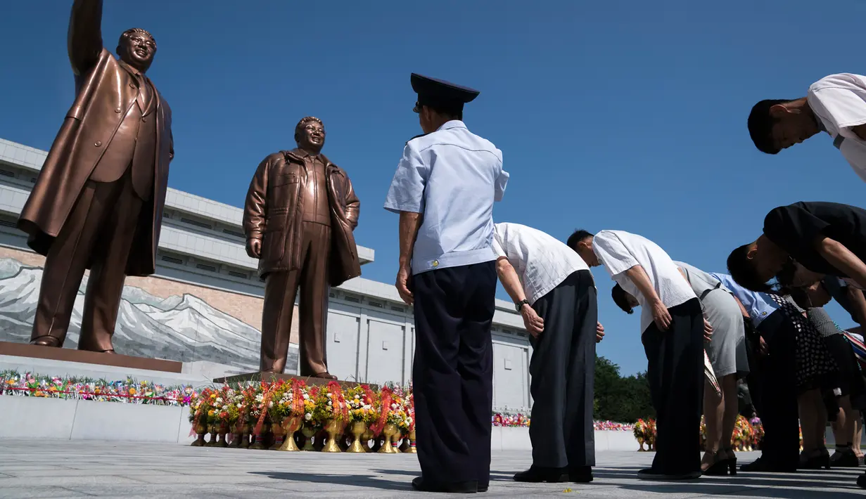 Penduduk membungkuk di depan patung pemimpin Korea Utara, Kim Il Sung dan Kim Jong Il di Bukit Mansu, Pyongyang, pada peringatan 24 tahun kematian Kim Il Sung, Minggu (8/7). Kim Il-sung memimpin Korut sejak 1948 hingga 1994. (AP Photo/Andrew Harnik, Pool)