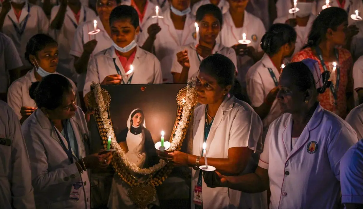 <p>Petugas kesehatan menyalakan lilin untuk menandai Hari Perawat Internasional di sebuah perguruan tinggi kedokteran pemerintah di Chennai, India, Jumat (12/5/2023). (R.Satish Babu/AFP)</p>