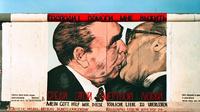 Mural Pemimpin Jerman Timur Erich Honecker berciuman dengan pemimpin Uni Soviet Leonid Brezhnev di Tembok Berlin pada masa Perang Dingin (Bundesarchiv/Joachim F Thurn via Wikimedia Commons)