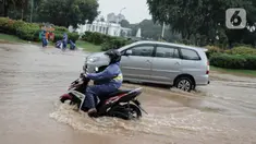 Kendaraan bermotor melintasi genangan air di Jalan Medan Merdeka Barat, Jakarta, Kamis (24/1/2020). Hujan deras yang mengguyur Jakarta sejak pagi tadi mengakibatkan genangan air di Jalan Medan Merdeka Barat. (Liputan6.com/Faizal Fanani)