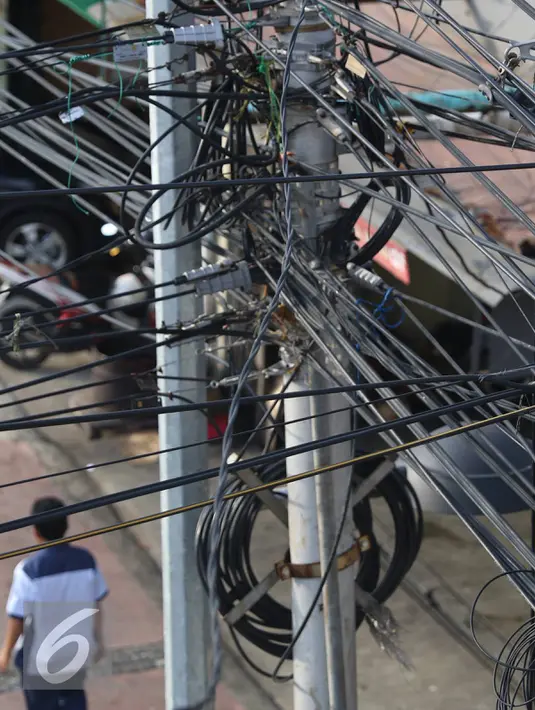 Instalasi kabel saling bersinggungan di tiang Jalan Gunung Sahari, Jakarta, Rabu (13/7). Kurangnya penataan membuat instalasi kabel di Ibu Kota terlihat semrawut dan mengganggu pemandangan. (Liputan6.com/Immanuel Antonius)