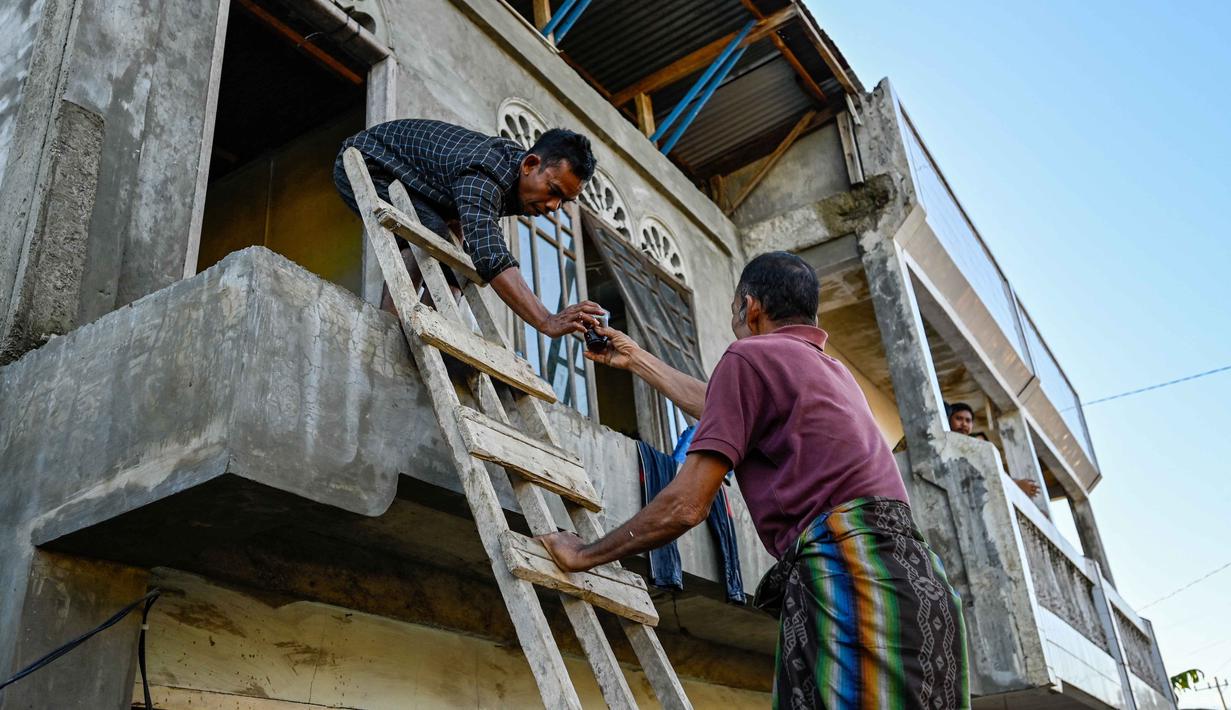 Saat ini, penanganan banjir Pidie Jaya kini memasuki fase respons cepat. Warga diminta tetap tenang di tempat pengungsian sambil menunggu bantuan yang segera dikirim melalui jalur udara dan darat. Tampak dalam foto, seorang pria berbagi kopi dengan seorang warga yang terlantar setelah banjir bandang di Meureudu, Kabupaten Pidie Jaya, Provinsi Aceh, pada 30 November 2025. (CHAIDEER MAHYUDDIN/AFP)