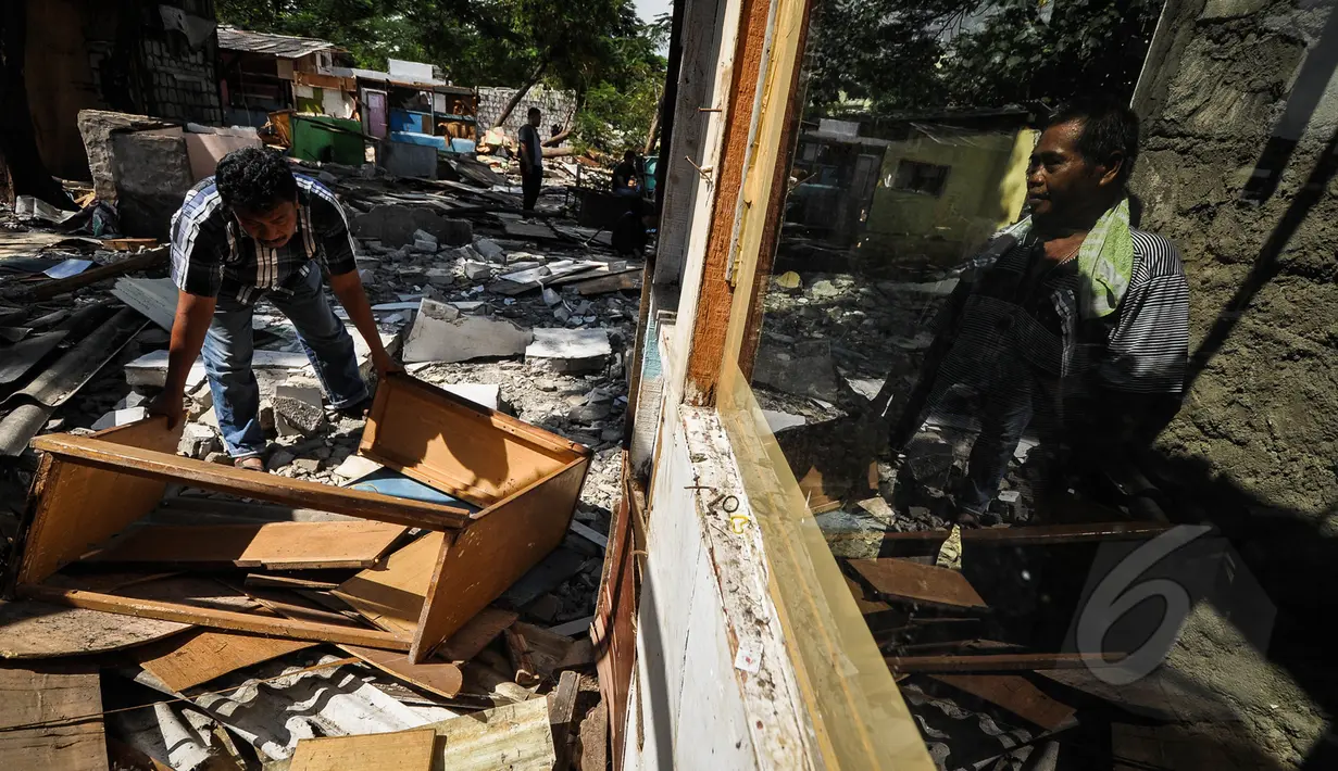 Warga mengambil sisa bangunan yang masih dapat digunakan seusai pembongkaran bangunan liar di sepanjang bantaran tanggul barat Kali Angke, Jakarta, Senin (30/3/2015). (Liputan6.com/Faizal Fanani)