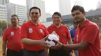 Gubernur DKI Jakarta, Basuki T Purnama menerima bola dari legenda hidup sepak bola Indonesia, Bambang Pamungkas saat membuka turnamen Rusun Cup 2015. (Bola.com/Vitalis Yogi Trisna)