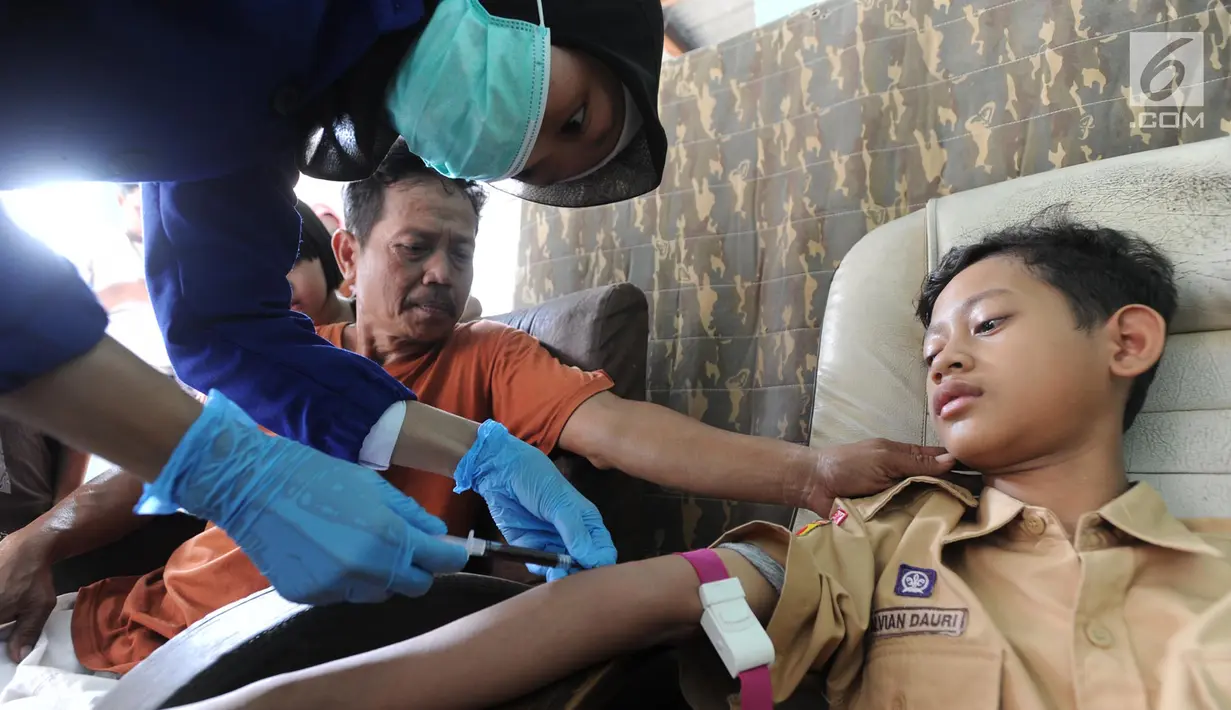 Seorang anak diambil sampel darah di RT1-2/1 Kelurahan Cinere, Depok, Rabu (28/6/2019). Dinas Kesehatan Depok dan Puskesmas Cinere melakukan investigasi sumber penyakit dan sampel darah warga di kawasan ini terkait sudah lebih dari sepekan 12 warga terjangkit hepatitis A. (merdeka.com/Arie Basuki)