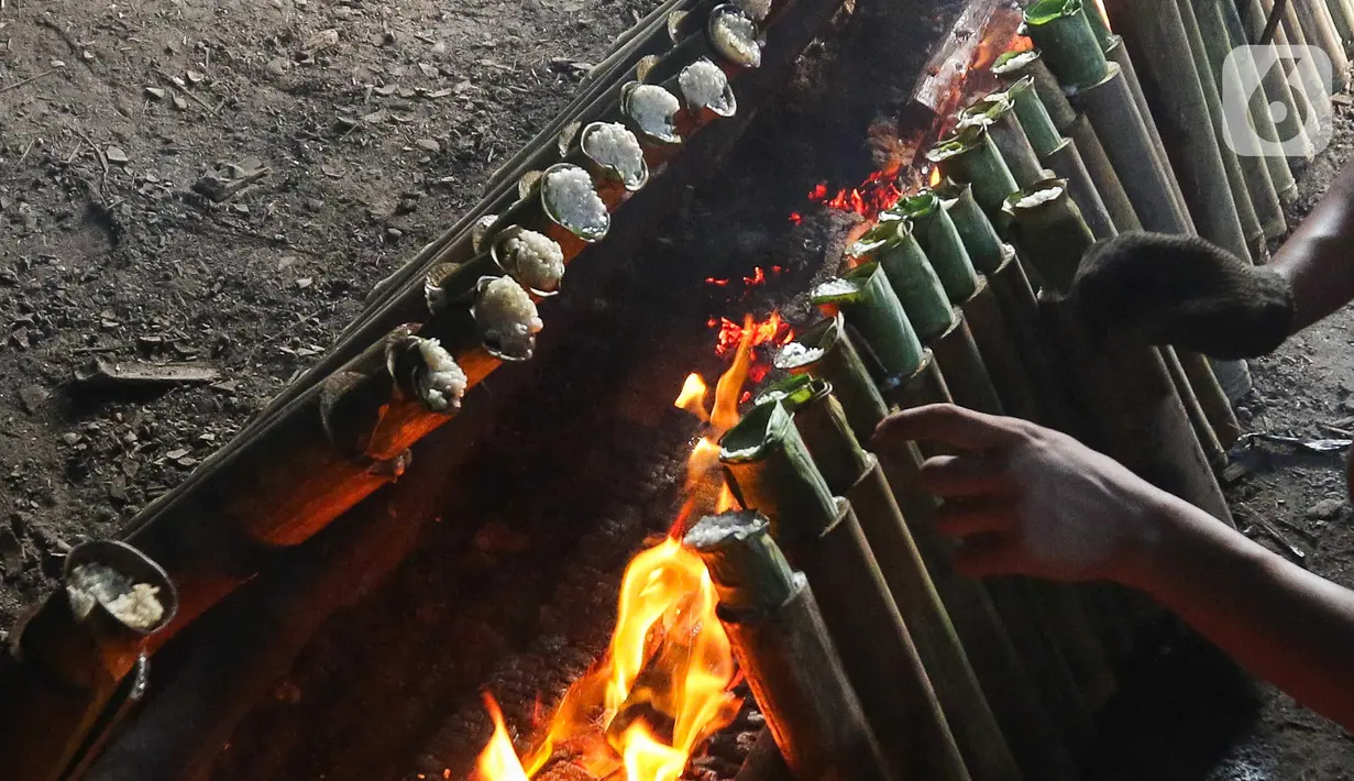 Pekerja membakar lemang di kawasan Kwitang, Jakarta, Minggu (9/3/2025). (Liputan6.com/Herman Zakharia)