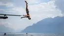 Seorang pria melompat ke Danau Jenewa di Saint Saphorin, Swiss barat saat gelombang panas melanda seluruh Eropa utara (31/7). Kondisi kekeringan di sebagian daerah diperkirakan akan terus berlanjut. (AFP Photo/Fabrice Coffrini)