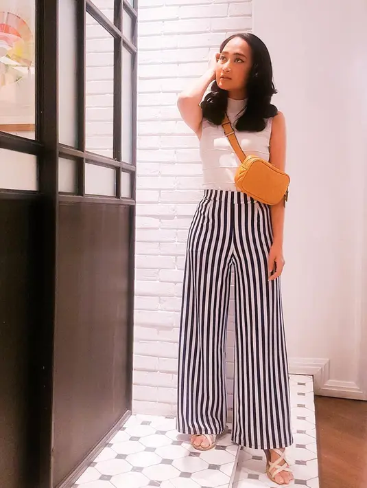 Memilih busana simpel dan bergaya kasual tak memudarkan pesona PJ. Kali ini ia tampil dengan tank top turtleneck putih yang dipadukan dengan kulot bermotif strip. Apalagi tas kuning yang ia kenakan menyempurnakan penampilannya. (Liputan6.com/IG/@nyonyahpjofficial)
