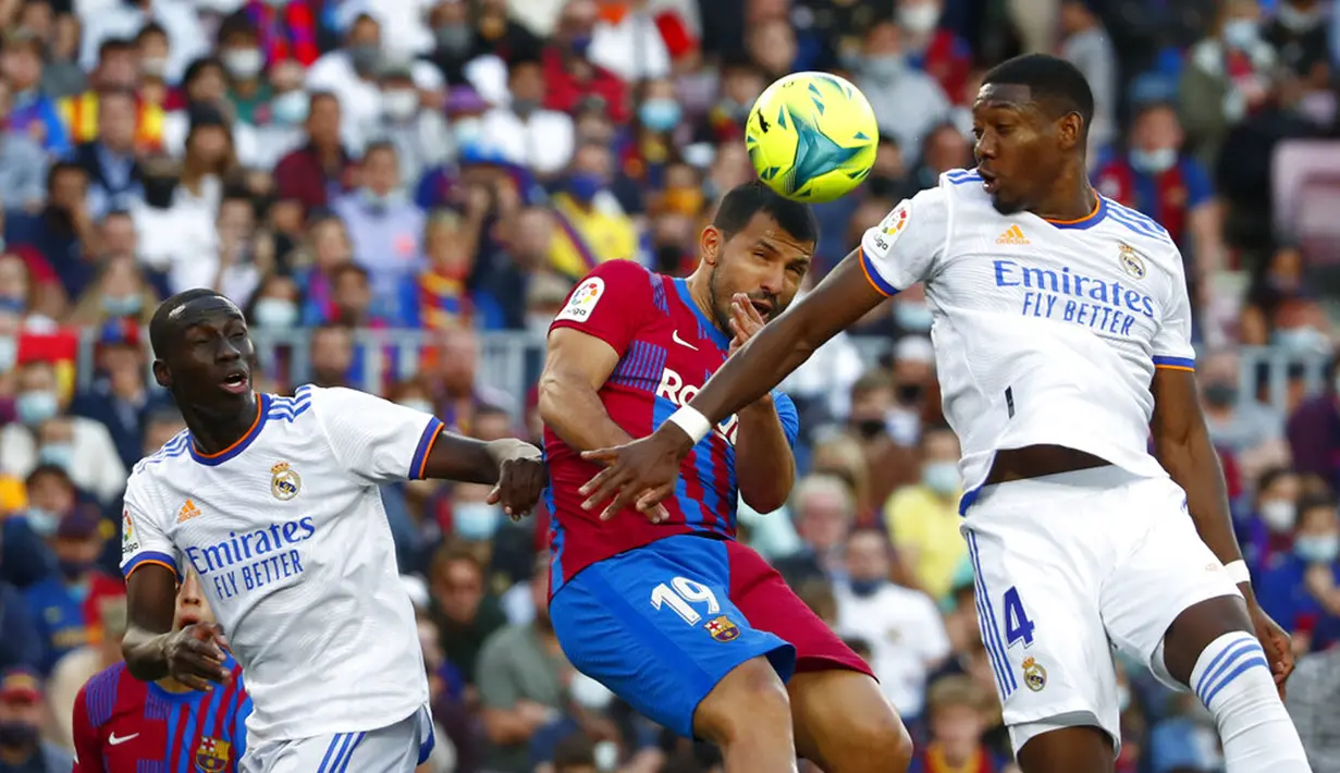 Pemain Barcelona Sergio Aguero (tengah) berebut bola dengan pemain Real Madrid David Alaba pada pertandingan La Liga Spanyol di Stadion Camp Nou, Barcelona, Spanyol, Minggu (24/10/2021). Real Madrid menang 2-1. (AP Photo/Joan Monfort)