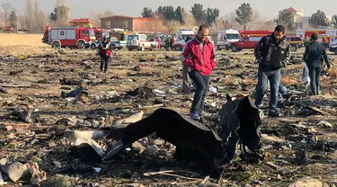 Orang-orang berjalan di antara puing-puing setelah pesawat Boeing 737 jatuh di dekat Bandara Internasional, Teheran, Iran, Rabu (8/1/2020). Seluruh penumpang pesawat maskapai Ukraina yang membawa 176 orang termasuk kru tersebut dilaporkan tewas. (AFP Photo)