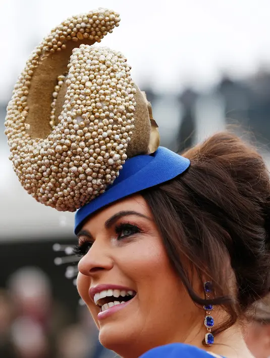 Seorang wanita tampil cantik dengan mengenakan topi yang unik jelang pembukaan ajang Pacuan Kuda dalam Festival Cheltenham di Inggris (16/3). Pacuan kuda merupakan olahraga yang disukai oleh kerajaan Inggris. (REUTERS/Paul Childs)