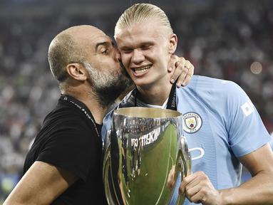 Pelatih Manchester City,  Pep Guardiola, mencium Erling Haaland saat perayaan juara UEFA Super Cup 2023 di Stadion Georgios Karaiskakis, Kamis (17/8/2023). Laga Piala Super Eropa kali ini berakhir imbang 1-1 dalam 90 menit, Man City menang 5-4 di babak adu penalti. (AFP/Spyros Bakalis)