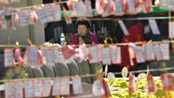 Seorang perempuan berdoa di depan deretan kertas untuk keberhasilan para siswa dalam ujian masuk perguruan tinggi di kuil Buddha Jogye, Seoul, Kamis (14/11/2019). Ujian masuk perguruan tinggi disebut-sebut sebagai ujian pertaruhan hidup para pelajar Korea Selatan. (Jung Yeon-je / AFP)