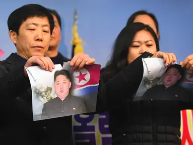 Warga Korea Utara yang membelot merobek foto pemimpin Korea Utara Kim Jong-Un saat konferensi pers di Majelis Nasional di Seoul (24/1). (AFP Photo/Jung Yeon-Je)